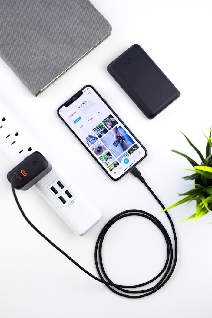 journey Top view composition of modern switched on mobile phone recharging on white table near tablet and green plant
